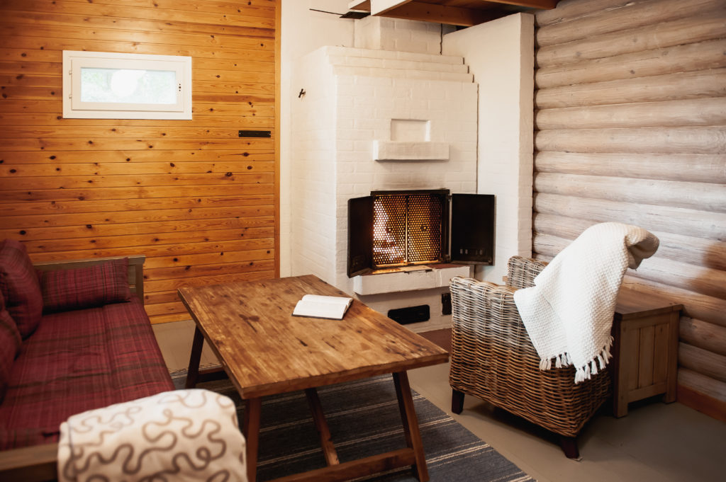 Living room of cottage where there is a sofa, an armchair, a sofa table, and a fireplace.