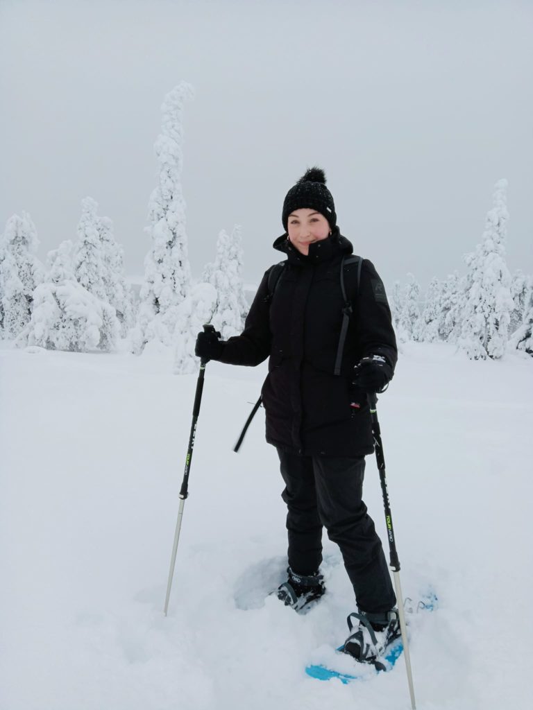 A girl wearing snowshoes stands in snow.