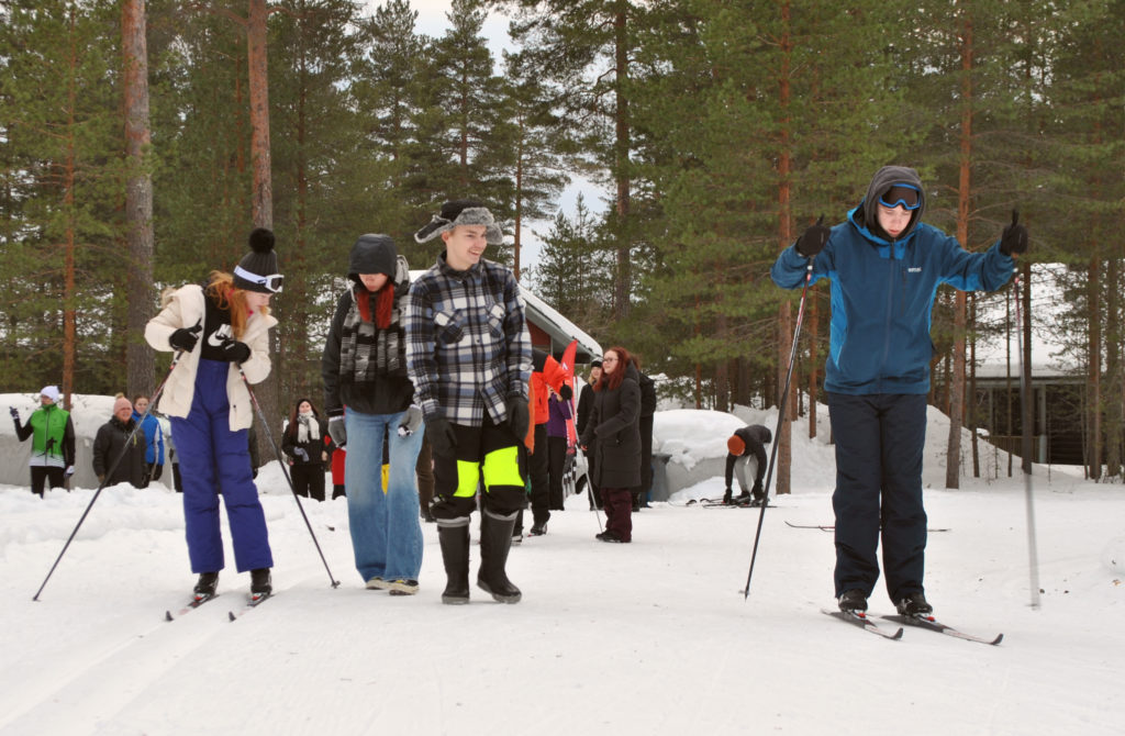Irlantilaiset nuoret opettelevat hiihtämään suomalaisnuorten avustamana. 