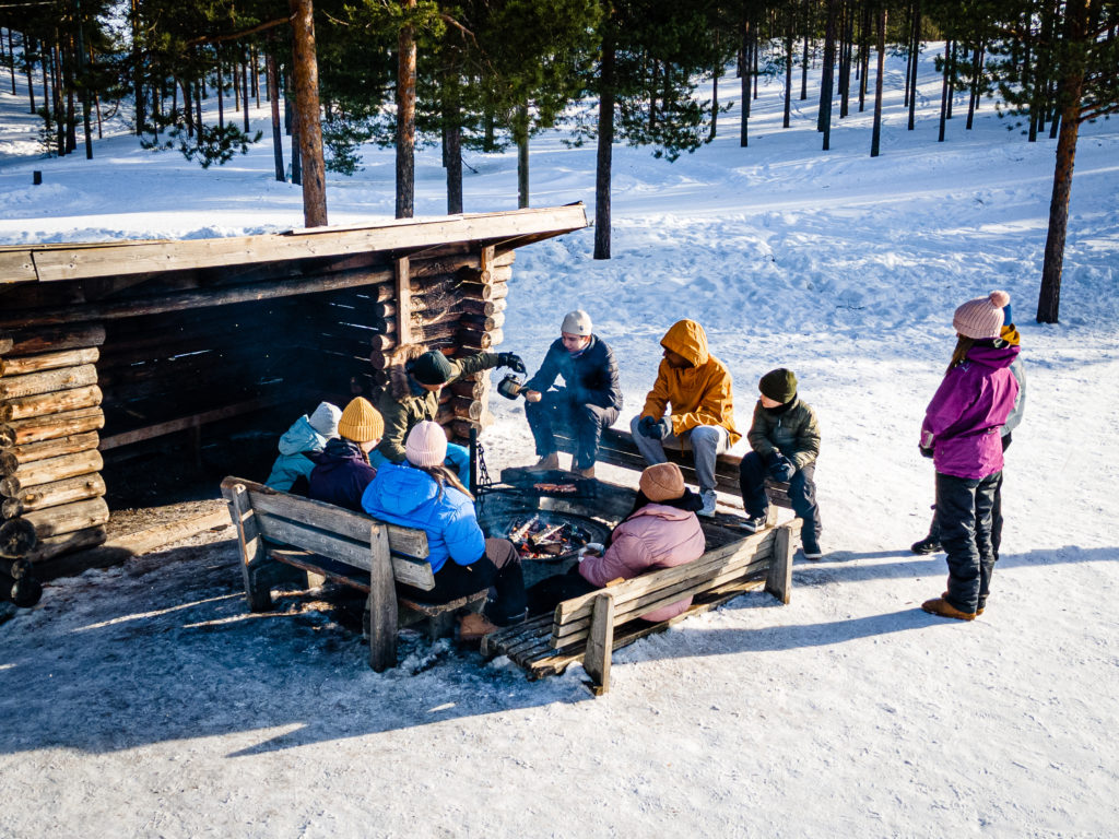 Ryhmä nuoria istuu talvisella laavulla.