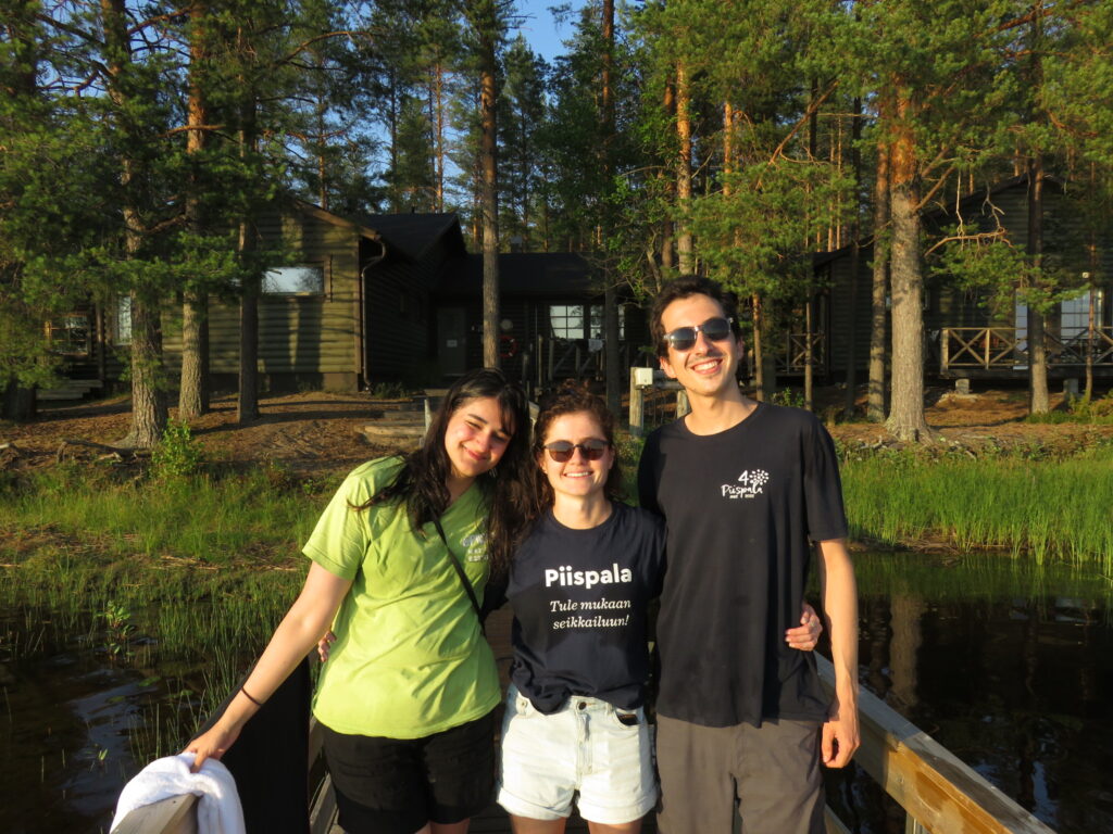 Kolme nuorta seisoo iloisina Piispalan laiturilla hymyillen.
