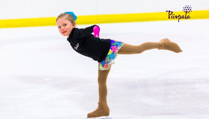 Nuori taitoluistelija harjoittelee jäähallissa.