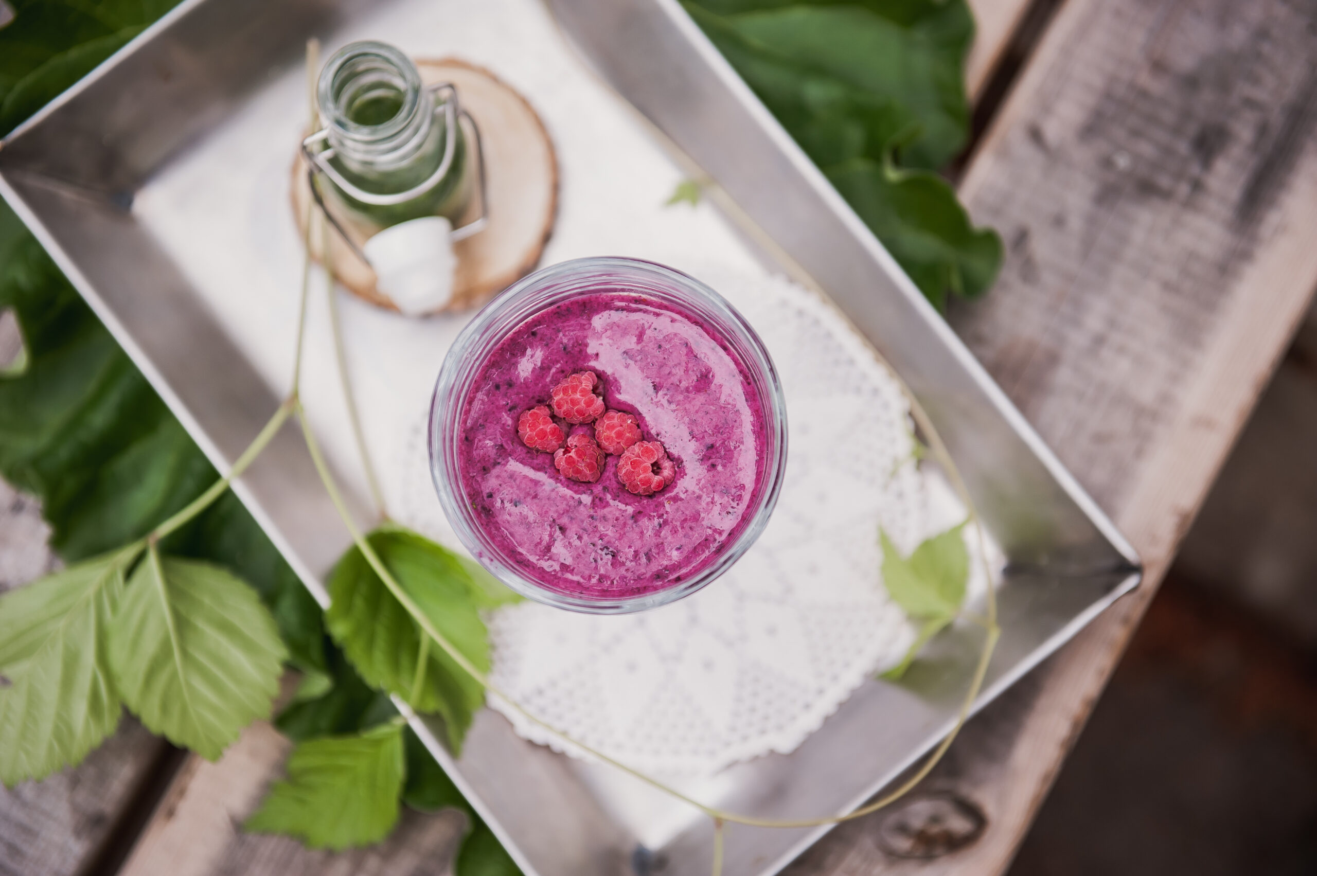 Marjaisa smoothie sekä yrttijuoma tarjottimella.